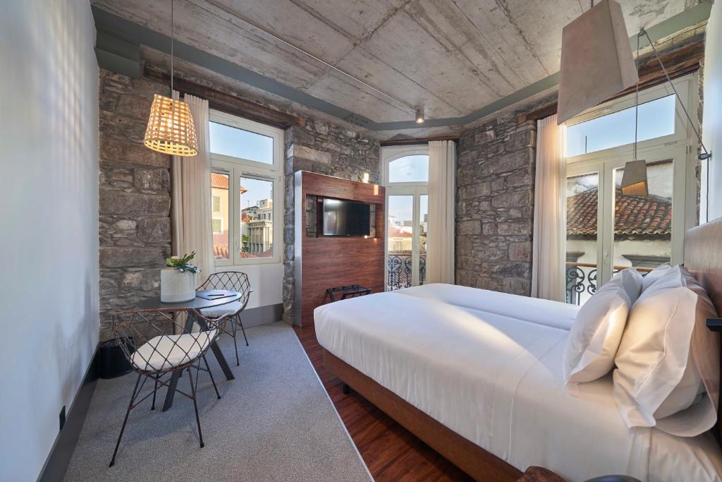 um quarto com uma grande cama branca e uma mesa em Hotel Cajú no Funchal