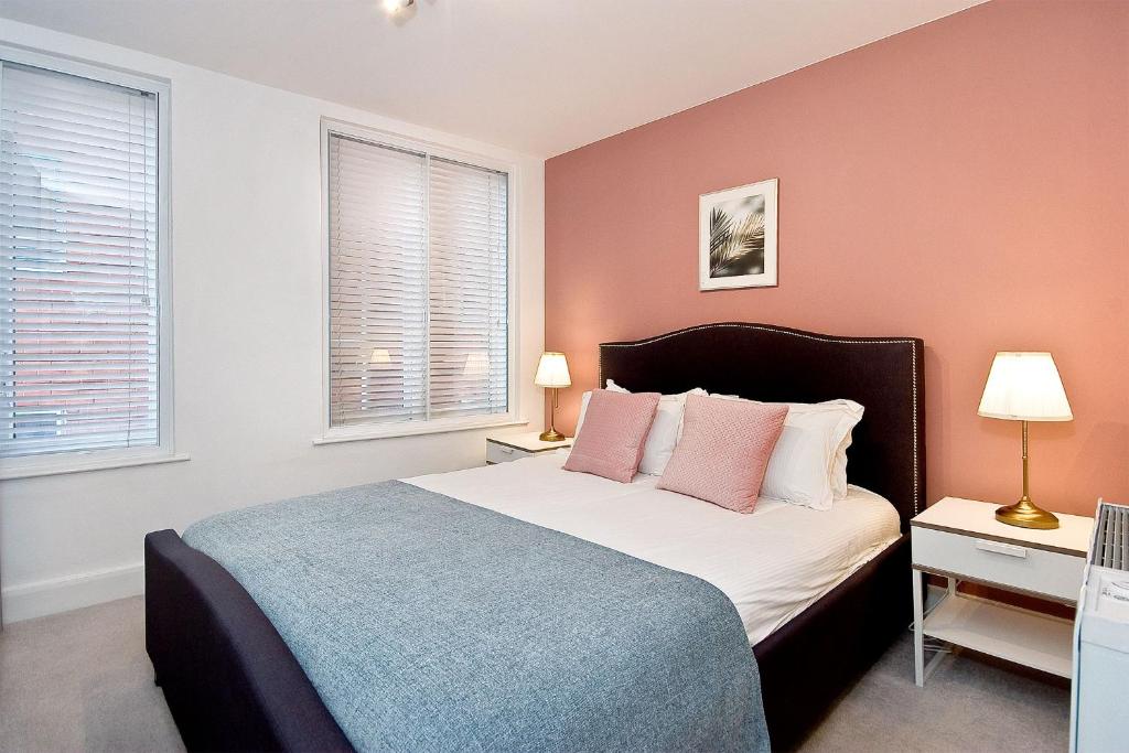una camera da letto con un letto con pareti rosa e due lampade di Mulberry Flat 6 - Two bedroom 3rd floor by City Living London a Londra