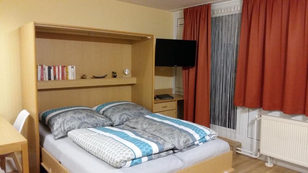 een slaapkamer met een bed, een televisie en een raam bij Herzerl Apartment in Sankt Englmar
