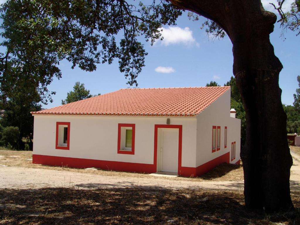 una pequeña casa blanca y roja con un árbol en Herdade Rodrigo Afonso en São Teotónio