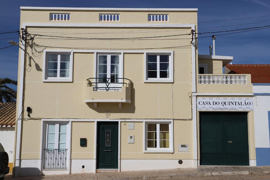 - un bâtiment jaune avec des portes vertes et un balcon dans l'établissement Casa do Quintalão, à Raposeira