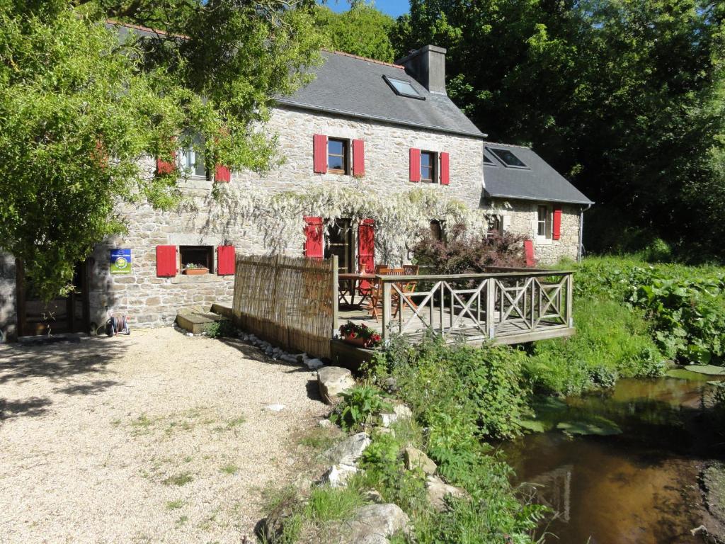 GuissényにあるChambres d'Hôtes du Moulin de Brendaouezの赤い窓と橋のある古い石造りの家