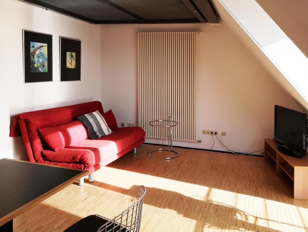 een woonkamer met een rode bank en een tv bij Boardinghouse-Modernes Dachstudio in guter Lage in Erfurt