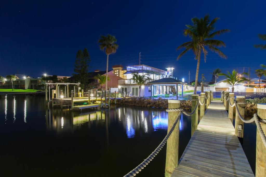 a dock with a house and palm trees at night at Lost Inn Paradise in Cocoa Beach