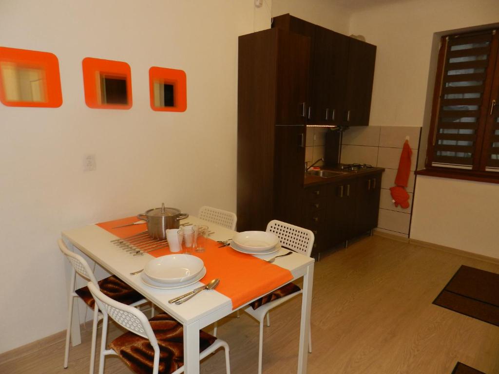 a kitchen with a white table with chairs and orange table cloth at Studio S. in Braşov