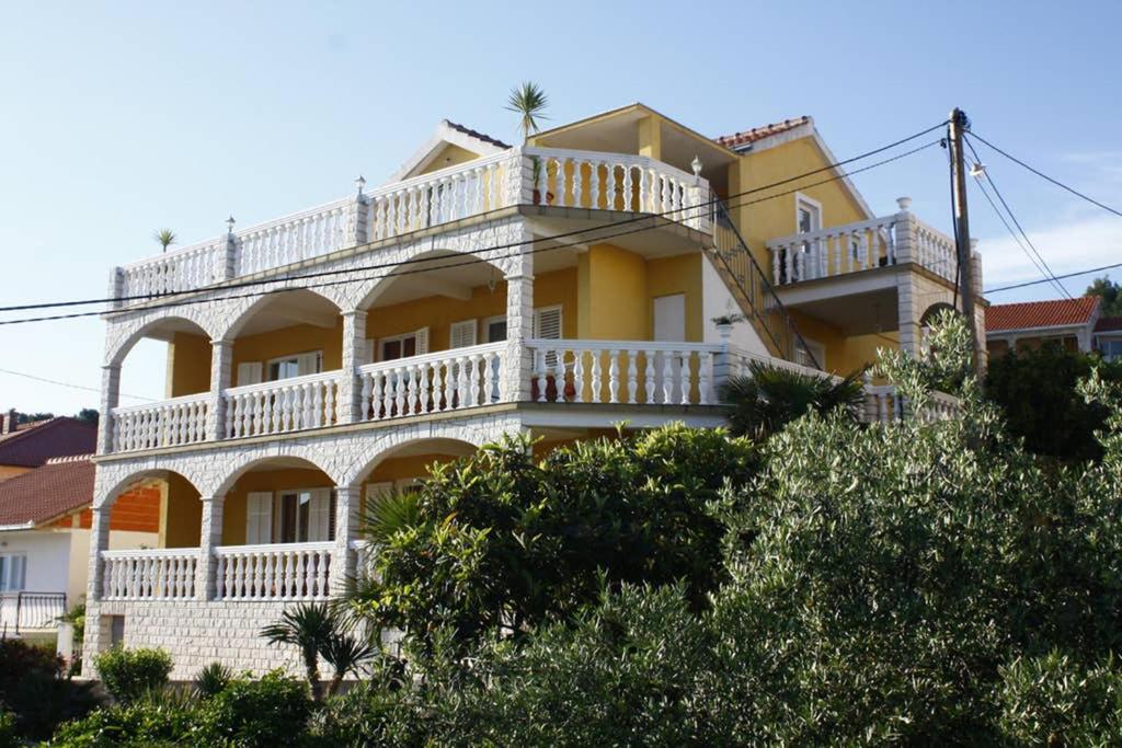 a large yellow building with a white balcony at Apartmen Karmen 2 in Trogir