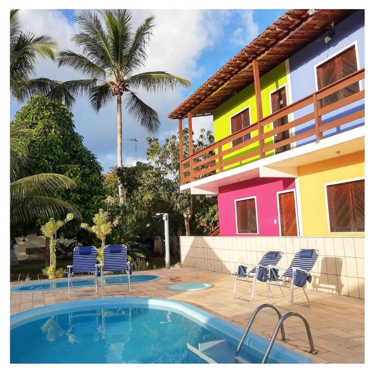 a house with chairs and a swimming pool in front of it at Pousada Villa Graciela in Ilhéus