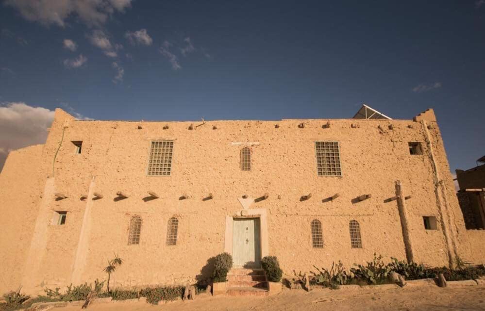a large brick building with a white door on it at Barbara’s House in Siwa