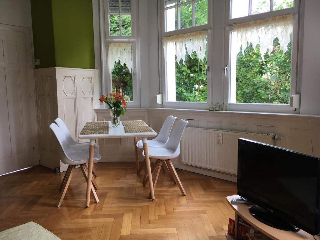 una sala da pranzo con tavolo, sedie e finestre di Appartment im Villenviertel a Jena