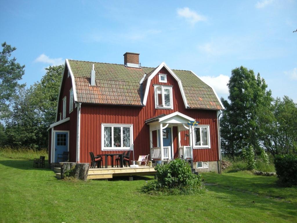 ein rotes Haus mit einer Terrasse im Gras in der Unterkunft Klappa in Malmbäck