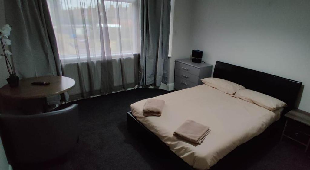 a bedroom with a bed and a table and a window at Just Like Home in Bristol