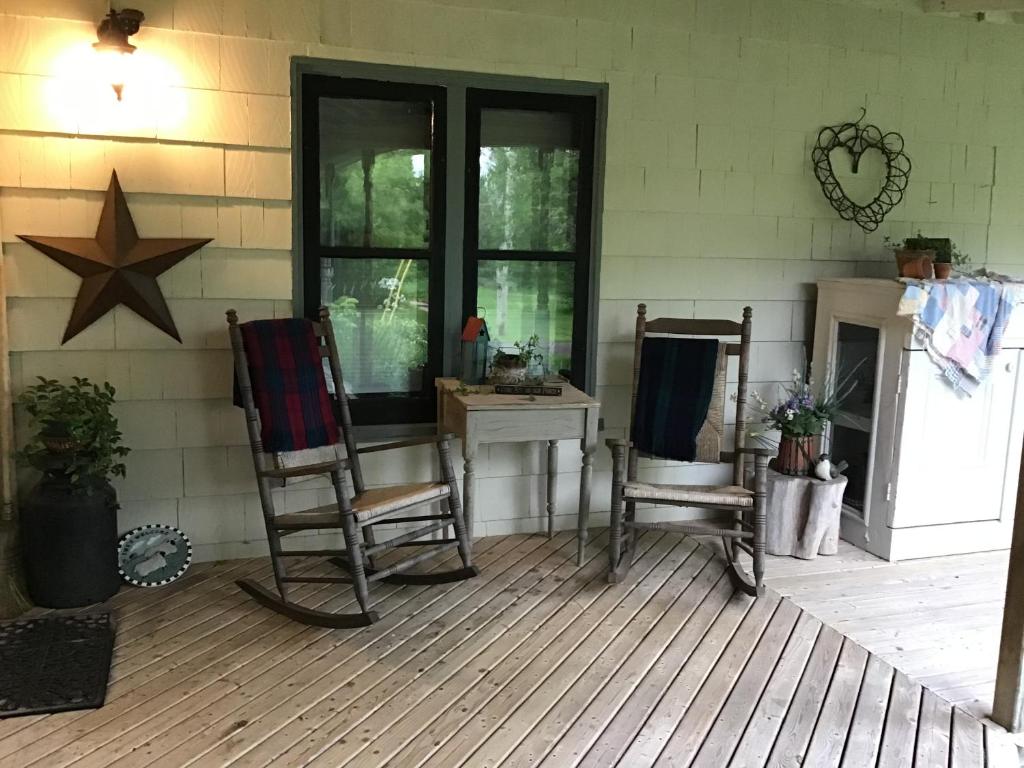 un porche con mesa y 2 mecedoras en Guest Suites at Willowgreen Farm, en Summerside