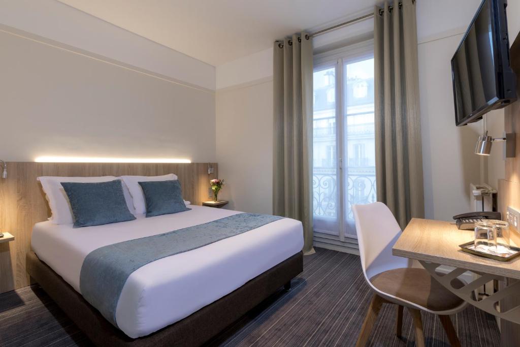 Habitación de hotel con cama, escritorio y TV. en Hôtel Opera Lafayette en París