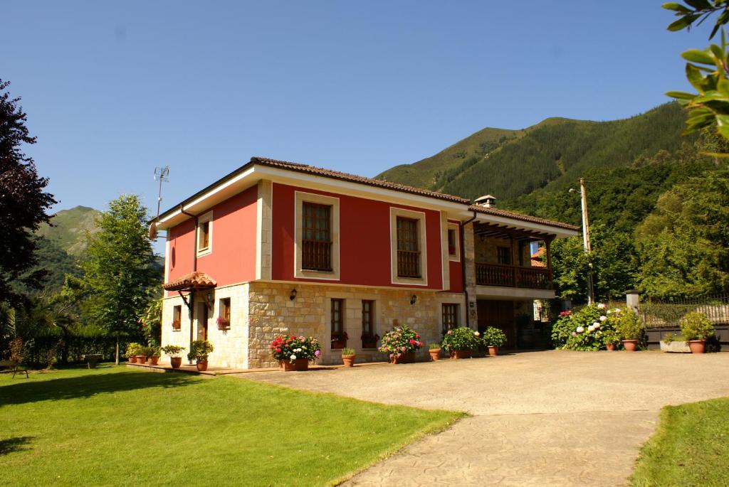 a large red house with mountains in the background at Casa Marian in Cangas de Onís
