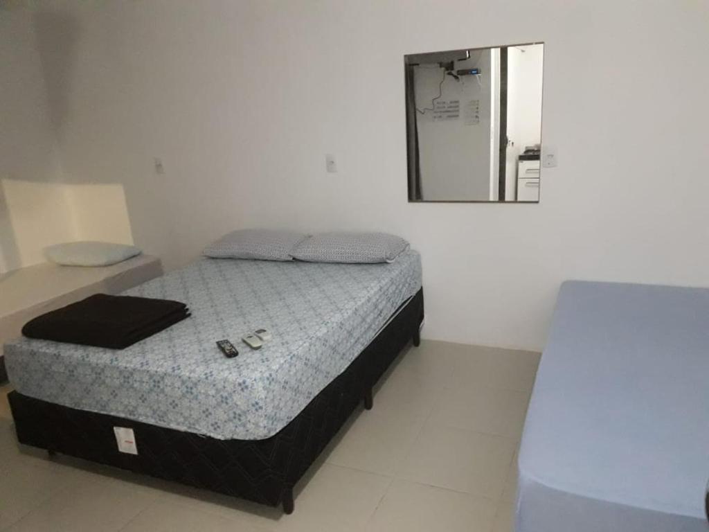 Cama pequeña en habitación con espejo en Pouse Bem, en Blumenau