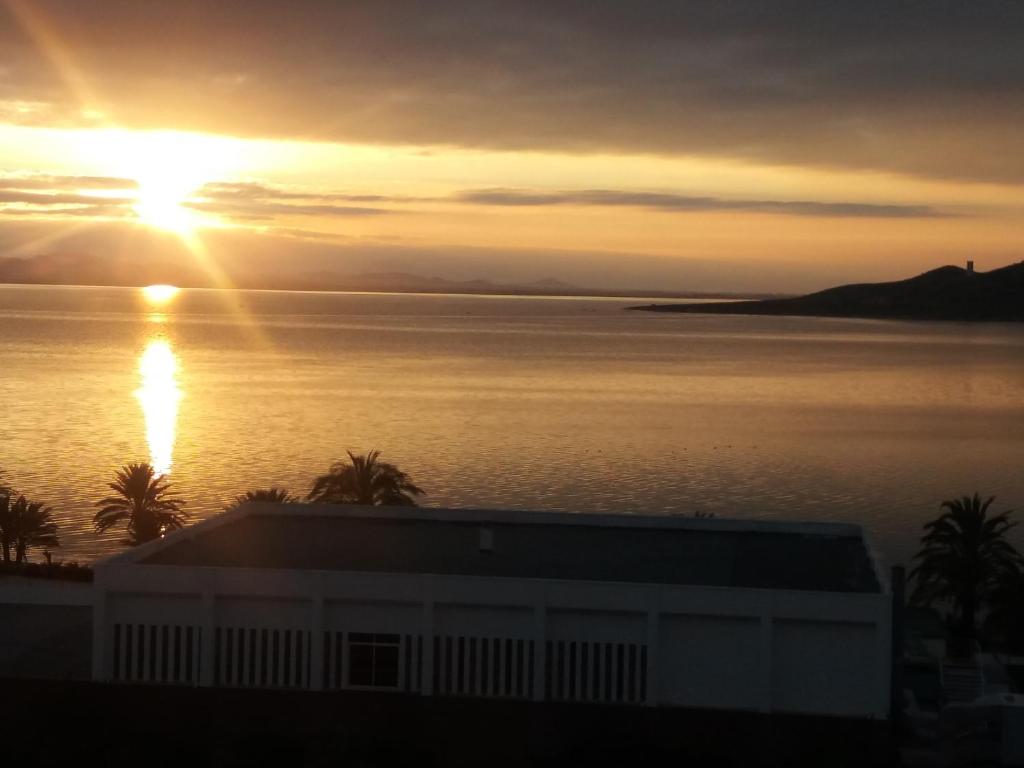 a sunset over a body of water with a building at LOFT DOS MARES- Parking Gratis - 1 Línea de Mediterráneo - Terraza - WIFI in La Manga del Mar Menor