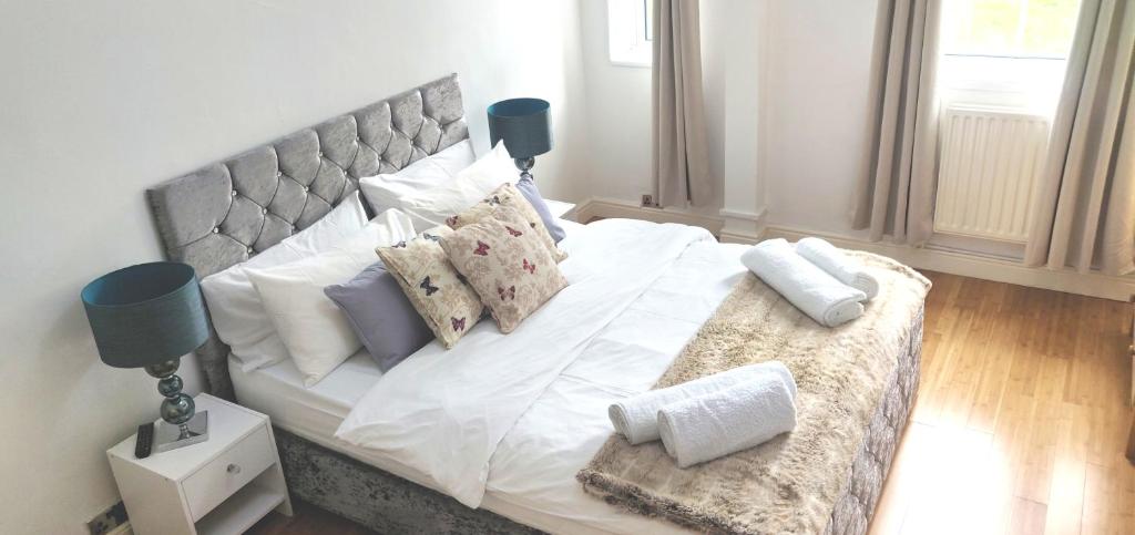 um quarto com uma cama grande com lençóis brancos e almofadas em Insignia Moment, London em Londres