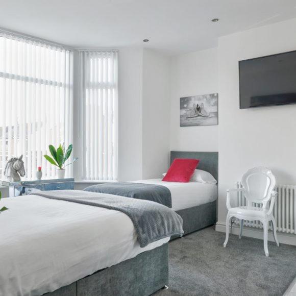 a bedroom with two beds and a tv and a chair at Priory Suites in Liverpool