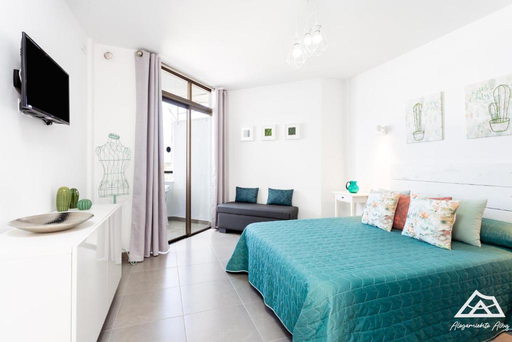 a white bedroom with a bed and a tv at Alojamiento Alby: Oceano in Los Cristianos