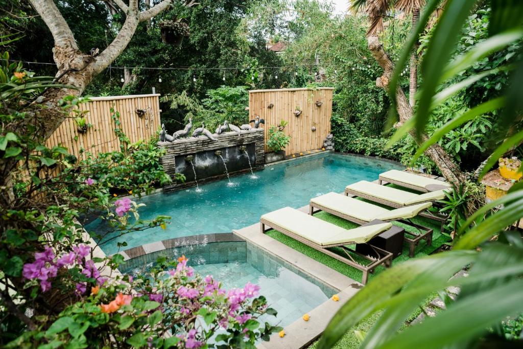 a swimming pool with lounge chairs in a garden at Desak Putu Putra Hidden in Ubud