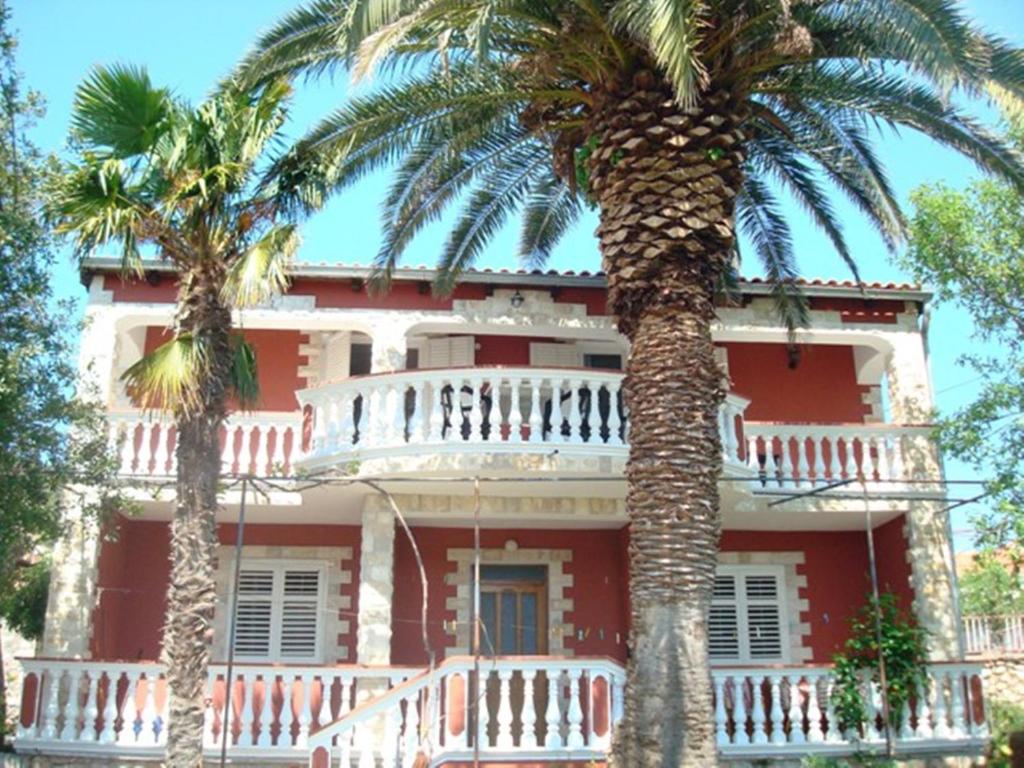 una casa roja con palmeras delante en Apartments Nicole, en Jezera