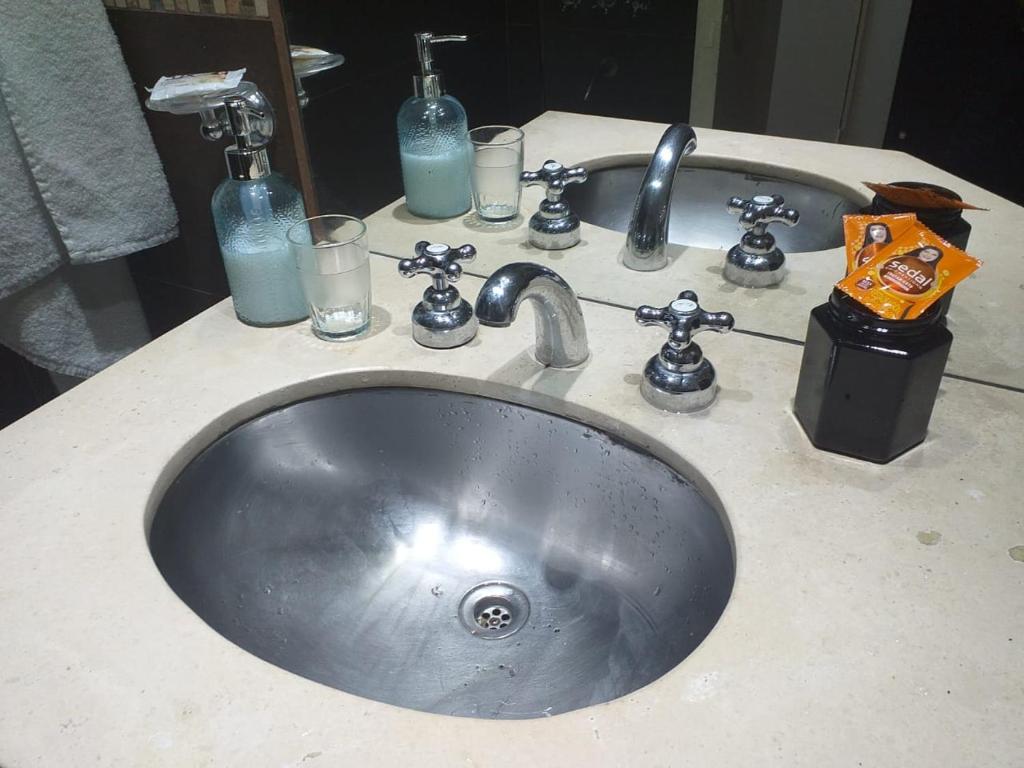 a sink with glasses and bottles on a bathroom counter at Gran vista desde el centro de la ciudad in Buenos Aires