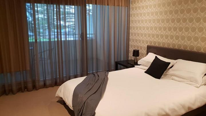 1 dormitorio con cama blanca y ventana grande en Glenelg Getaway 3 bedroom apartment when correct number of guests are booked, en Glenelg