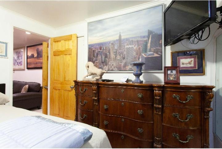 a bedroom with a dresser with a painting on the wall at Studio Apartment in Irvington