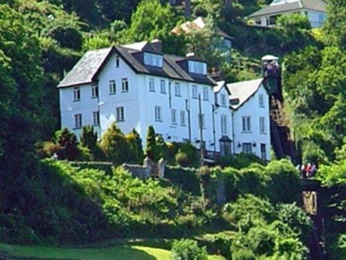 uma grande casa branca no lado de uma colina em The North Cliff Hotel em Lynton