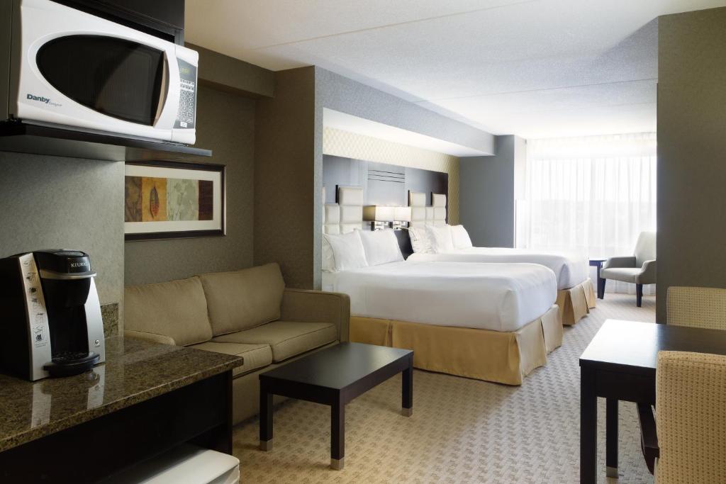 a hotel room with a bed and a couch at Holiday Inn Express & Suites Ottawa West - Nepean by IHG in Ottawa