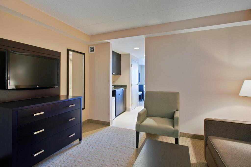 a living room with a television and a chair at Holiday Inn Express & Suites Ottawa West - Nepean by IHG in Ottawa