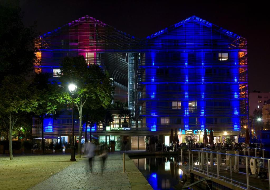 a building with blue lights on it at night at Holiday Inn Express Paris-Canal De La Villette, an IHG Hotel in Paris