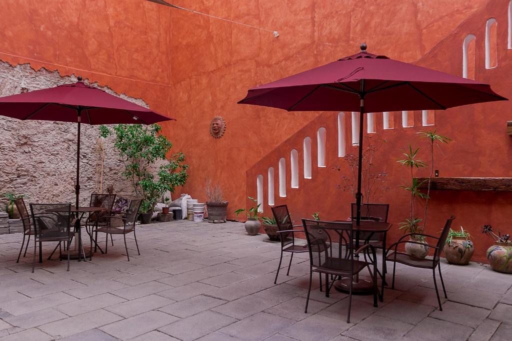 eine Terrasse mit Tischen, Stühlen und Sonnenschirmen in der Unterkunft Hotel el Descanso in Puebla