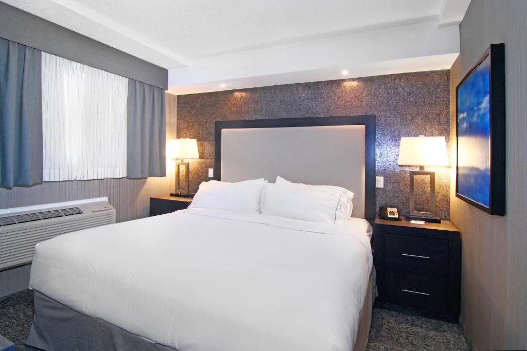 a hotel room with a large white bed and a window at Holiday Inn Express and Suites Calgary by IHG in Calgary
