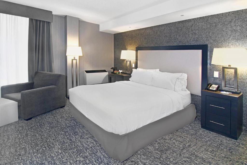 a bedroom with a large white bed and a chair at Holiday Inn Express and Suites Calgary by IHG in Calgary