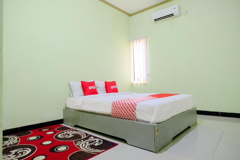 Schlafzimmer mit einem Bett mit roten Kissen und einem Teppich in der Unterkunft OYO Life 2508 Alba Suites Homestay Syariah in Tulungagung