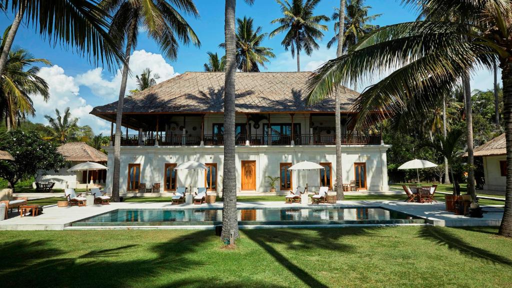 a house with a swimming pool and palm trees at Villa Mandala in Jasri