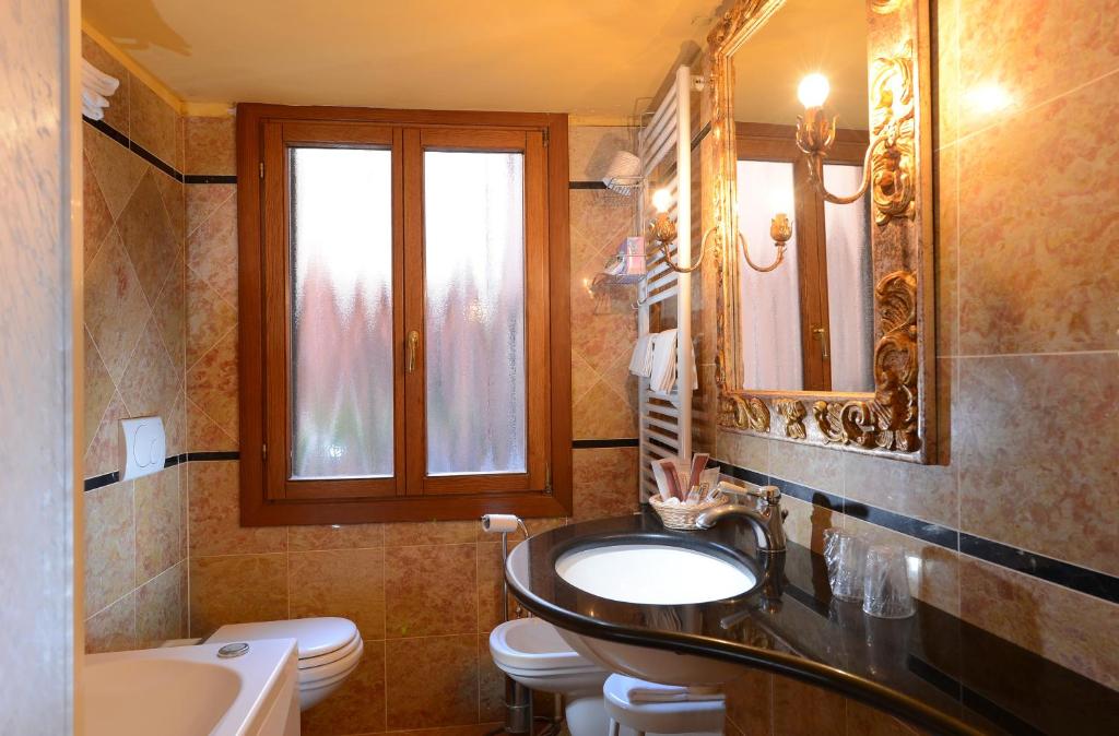 a bathroom with a sink and a toilet and a mirror at Antico Panada in Venice