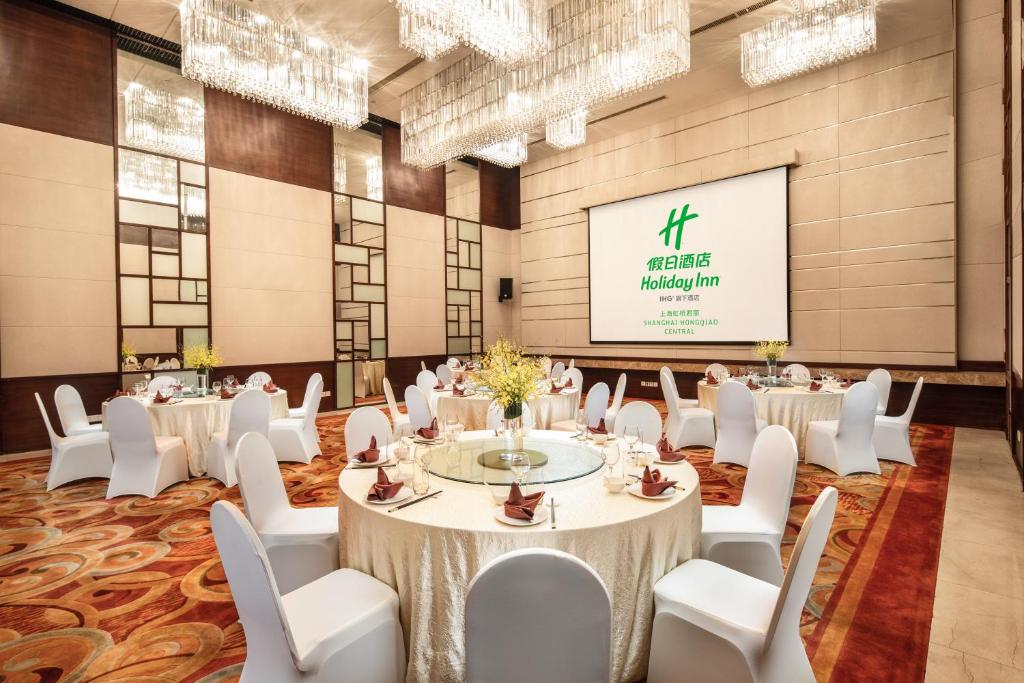 a conference room with white tables and chairs and a screen at Holiday Inn Shanghai Hongqiao Central, an IHG Hotel in Shanghai