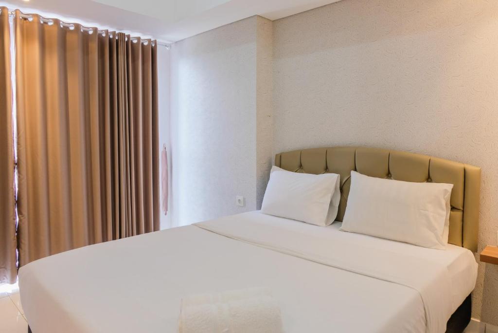 ein Schlafzimmer mit einem großen Bett mit weißen Laken und Kissen in der Unterkunft Minimalist Studio Apartment at Casa De Parco By Travelio in Samporo