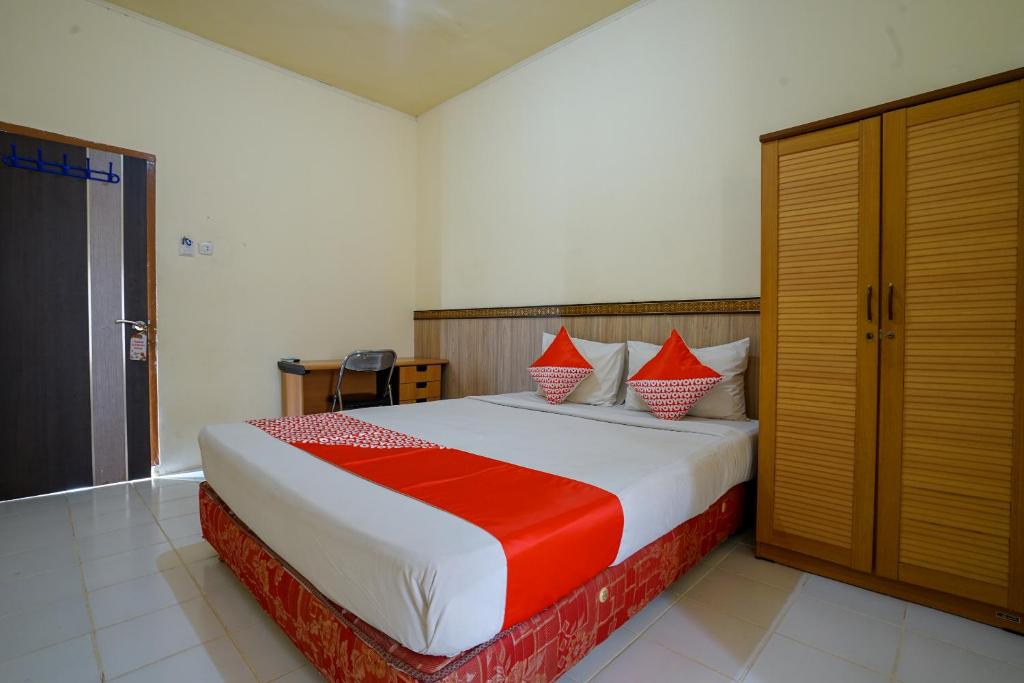 a bedroom with a large bed with red and white pillows at OYO Life 2502 Syariah Triantama Kost in Palembang