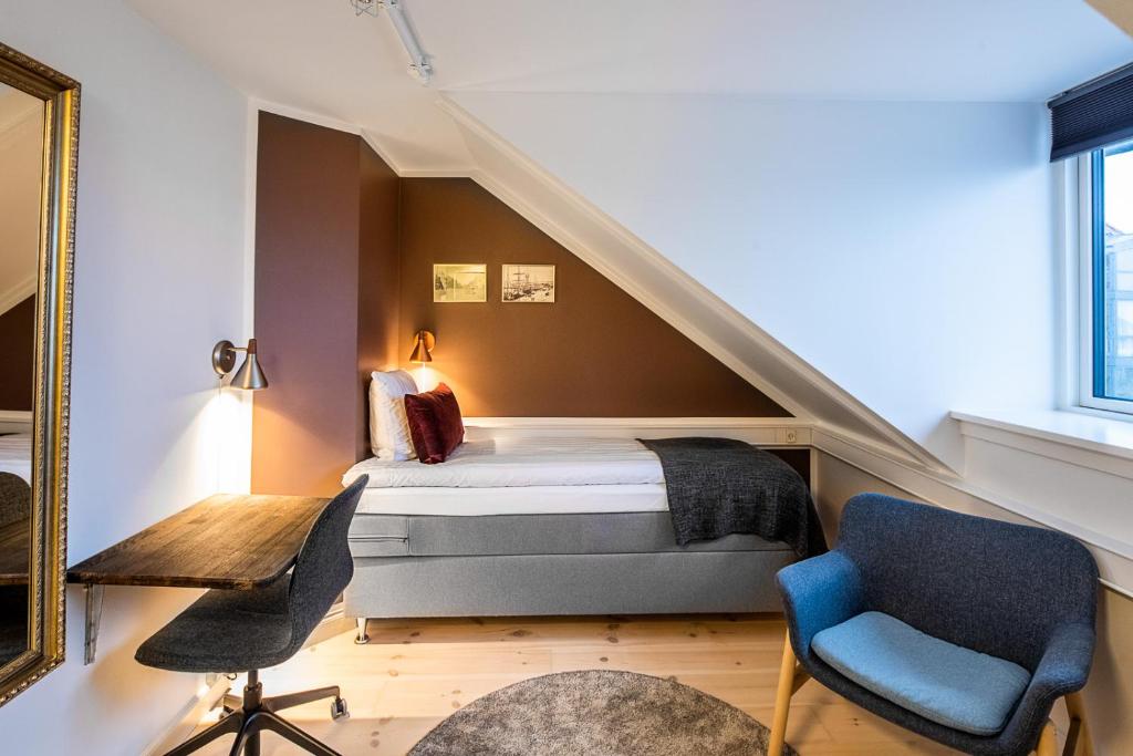 een slaapkamer met een bed, een bureau en stoelen bij Hotel Sidesporet in Holbæk