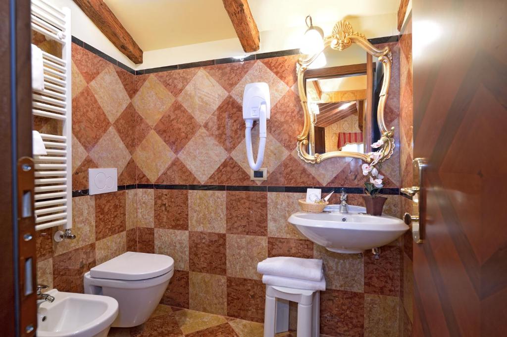 W łazience znajduje się umywalka, toaleta i lustro. w obiekcie Antico Panada w Wenecji