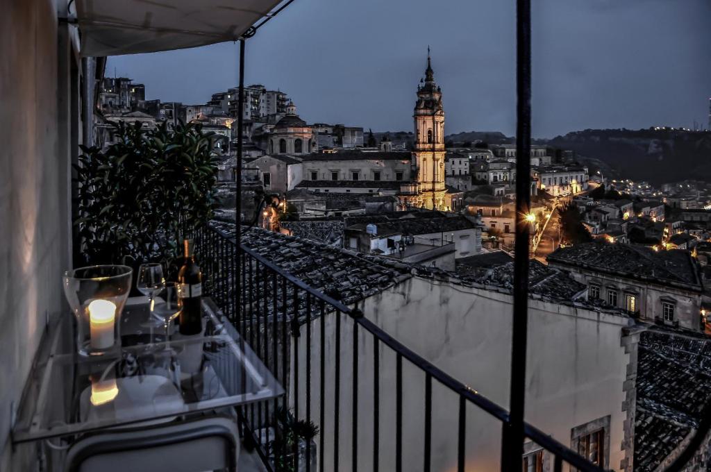 a balcony with a view of a city at night at Anime a Sud - Casa Kimiyà in Modica