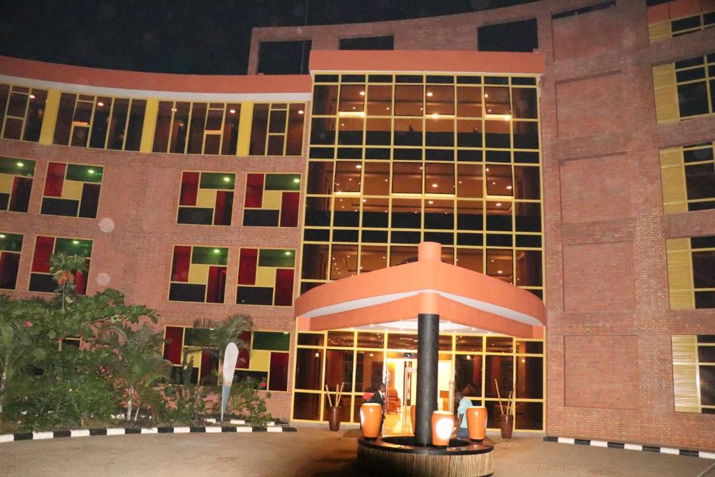 - un grand bâtiment la nuit avec un parasol devant dans l'établissement Sainte Famille Hotel, à Kigali