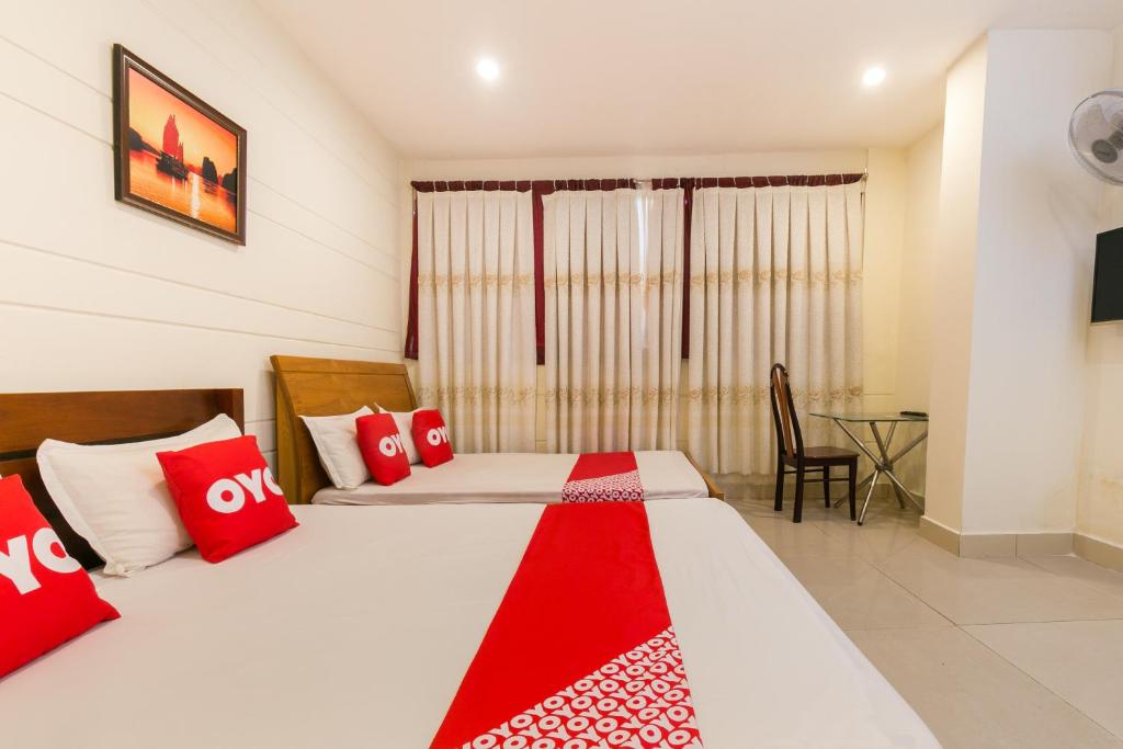 a bedroom with two beds with red and white pillows at Aqua Hoa My Hotel in Ho Chi Minh City