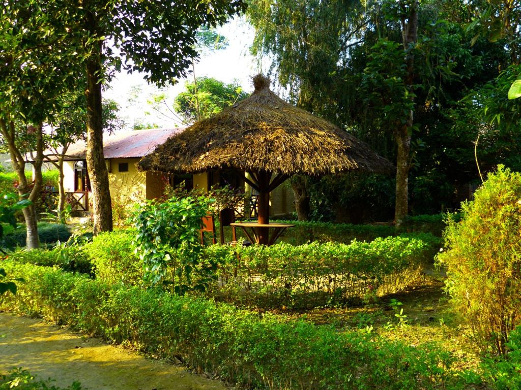 a hut with a straw umbrella and a table at Nature Safari Resort in Bhurkīā