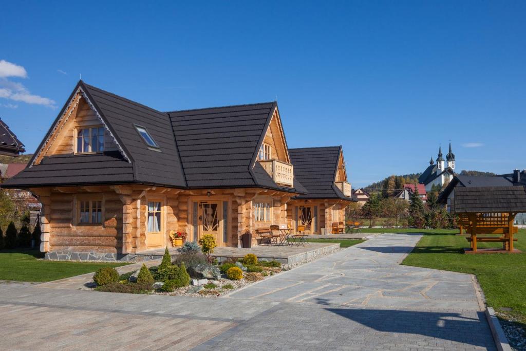 uma grande casa de madeira com um telhado preto em Całoroczne Domki Góralskie Kluszkowce-Czorsztyn em Kluszkowce