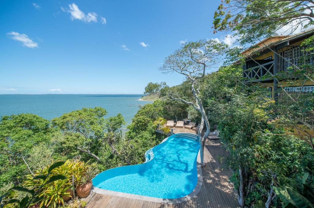 einen Blick über einen Pool neben dem Meer in der Unterkunft Pousada Enseada das Garças in São Pedro da Aldeia