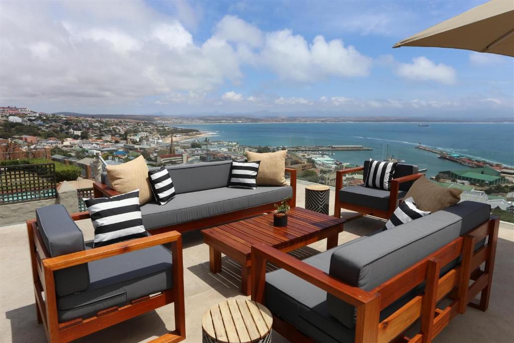 a patio with a table and chairs and the ocean at The Lookout Guest House in Mossel Bay